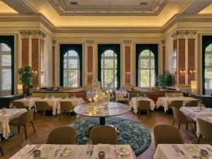 巴德加斯坦Straubinger Grand Hotel Bad Gastein的用餐室设有桌椅和窗户。