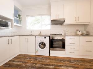 德班Secure, Peaceful Modern Cottage for Two的厨房配有白色橱柜和洗衣机。