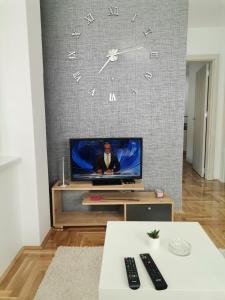波扎雷瓦茨JOKER Apartman的客厅配有电视和墙上的时钟