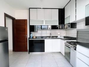 贝鲁特Modern 3BR Apt next to Hotel Dieu的厨房配有白色橱柜和黑色冰箱。