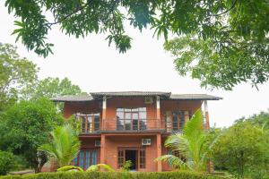 锡吉里亚Sigiriya Cottage的红砖房子,设有阳台和树木