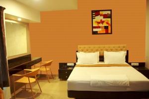 索拉普Hotel Vaishnavi的卧室配有床、电视和椅子