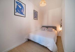 马赛Maison au cœur de l’Estaque的卧室配有白色的床和墙上的两张照片
