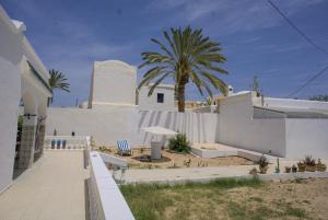 伊里德Wostel Djerba的一座白色的建筑,背后是棕榈树