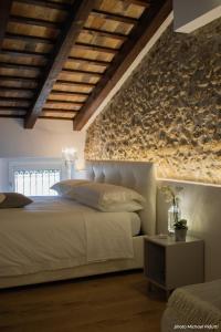 弗留利地区圣达尼埃莱Affittacamere CASA DOLCE CASA SAN DANIELE的卧室配有白色的床和石墙
