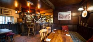 埃格顿The Postgate Inn的餐厅设有酒吧,配有木桌和椅子