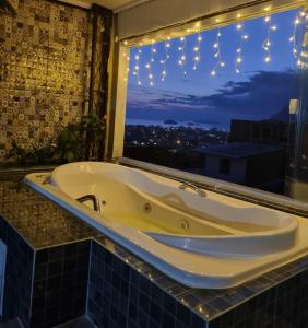 曼加拉蒂巴Suite Bela vista Muriqui Cantinho Feliz的带浴缸的浴室,浴室设有窗户和灯