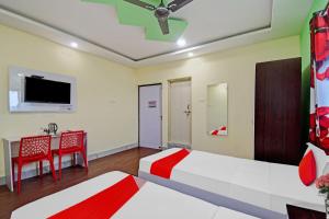 布巴内什瓦尔OYO Flagship Hotel Greenmoods的一间卧室配有两张床、一张桌子和一台电视。