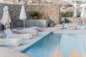 克洛瓦斯Oliving Mykonos Luxury Suites的毗邻度假酒店的带椅子和遮阳伞的游泳池