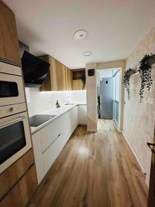 雷乌斯Premium Aparthotel-PortAventura, FerrariLand,tren的厨房铺有木地板,配有白色橱柜。