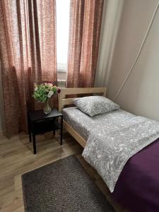 阿克套Гостевой Отель-125的一间卧室配有一张床和一张花瓶桌子