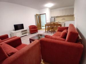 佩奇Pejë的一间带两张红色沙发的客厅和一间厨房