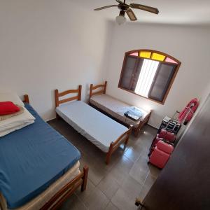 佩鲁伊比CASA DE PRAIA MARAVILHOSA PERUIBE的一间卧室设有两张床、一个窗口和一个行李箱