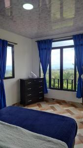 佩雷拉Hospedaje Villa Salome的一间卧室配有蓝色窗帘、一张床和窗户