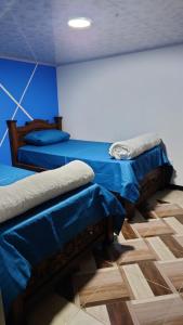 佩雷拉Hospedaje Villa Salome的蓝色墙壁客房的两张床