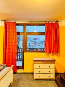 特普利采Thermal Apartments的一间卧室设有窗户,配有红色窗帘和梳妆台