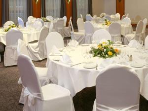 卢塞恩卢塞恩宜必思尚品酒店的一间设有白色桌椅、白色桌子和鲜花的客房