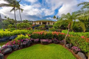 科洛阿考艾岛凯悦Spa度假酒店的一座花园,在房子前面种有鲜花和棕榈树