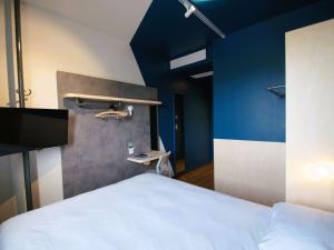 卢代阿克ibis budget Loudéac Vélodrome的卧室配有白色的床和蓝色的墙壁