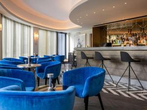 布鲁塞尔Le Louise Hotel Brussels - MGallery的一间设有蓝色椅子的餐厅和一间酒吧