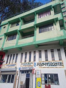 萨加达Pas-it Hostel Sagada的一座绿色的白色建筑,前面有标志