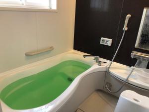 八户市青森伝統芸能を楽しめる繭子の宿的带绿色浴缸的浴室和卫生间