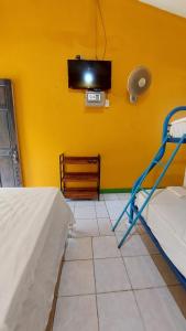 曼萨尼约Cool & Calm Hotel的一间黄色墙壁上配有电视的房间