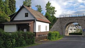 Nové HamryHoliday home Nove Hamry/Erzgebirge 1646的一座白色的小房子,在拱门旁设有红色屋顶