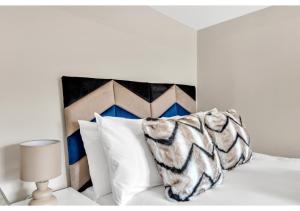 伦敦Stay & Explore: Convenient Studio - Prime Location的一张白色的床,配有黑白枕头和一盏灯