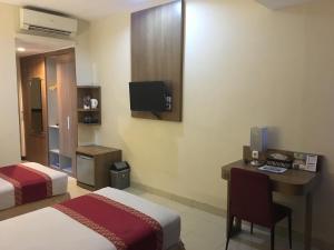 日惹University Club (UC) Hotel UGM的酒店客房设有两张床、一张桌子和一台电视。