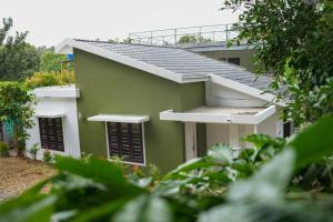 瓦亚纳德B'camp Resorts & Homestays的绿色和白色的建筑,有黑色百叶窗