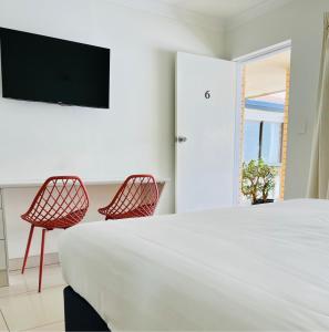 拜伦湾海湾汽车旅馆的一间卧室配有两把椅子和一张床