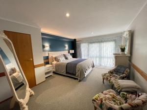 罗托鲁瓦Tikitere Lodge, Rotorua的一间卧室配有一张床、一把椅子和镜子