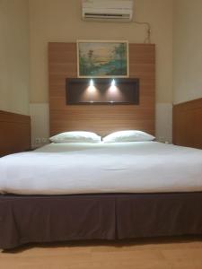 沙马林达Violand Garden Hotel Samarinda的一间卧室配有一张大床和木制床头板
