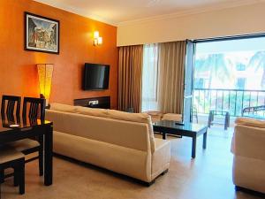 阿伯来Susegad Suites Goa Apartments & Villas Riviera Hermitage Arpora的带沙发和电视的客厅