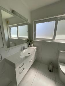 奥克兰Central Howick Uxbridge Apartments的白色的浴室设有水槽和镜子