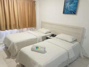 马六甲De Ocean Hotel的酒店客房设有两张床和窗户。