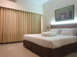 沙马林达Violand Garden Hotel Samarinda的一间卧室配有一张带白色床单的大床