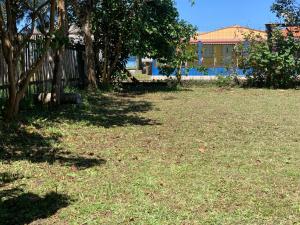 特拉曼达伊Casa de Praia的一座有树木和草地的院子和栅栏