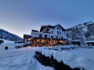 萨尔巴赫SKILL Mountain Lodge - Ski und Bike Hostel inklusive JOKER CARD的黄昏雪中的房子