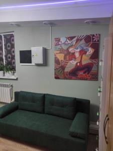 阿拉木图Hostel Nomad的客厅里一张绿色的沙发,上面有绘画作品