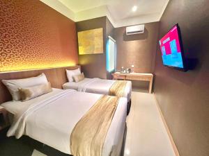 棉兰Deli Hotel的酒店客房设有两张床和一台平面电视。