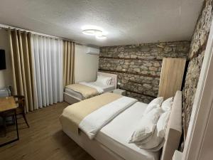 波格拉德茨Vila Ndrio的一间卧室设有两张床和石墙