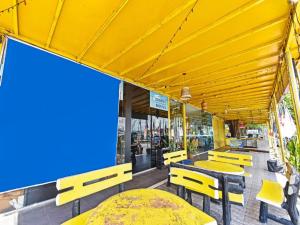 亚娄UMMUL MOTEL的一间设有黄色桌子和长凳的庭院餐厅