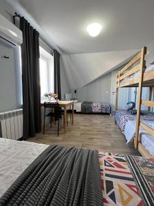 阿克套Гостевой Отель-125的客房设有两张床、一张桌子和一张双层床。