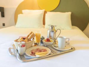 阿普瓦尼Mercure Auxerre Autoroute du Soleil的床上的托盘,包括早餐食品和饮料