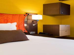 庞坦巴黎庞坦门美居酒店的一张位于酒店客房的床铺,配有白色的床
