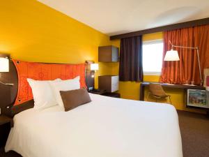 庞坦巴黎庞坦门美居酒店的酒店客房设有一张白色大床和黄色的墙壁。