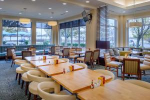 奥法隆圣路易斯/奥法隆希尔顿花园酒店的餐厅设有木桌、椅子和窗户。
