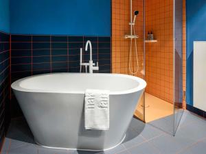 汉堡25hours Hotel Hamburg HafenCity的浴室设有浴缸,铺有蓝色和橙色瓷砖。